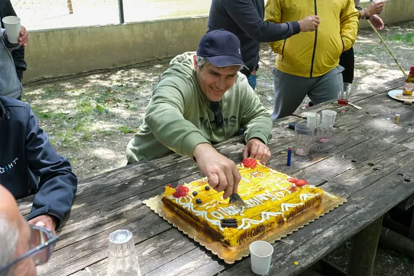 Colaborador da IHT a cortar o bolo do 17.º aniversário, num convívio ao ar livre