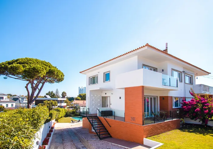 Villa à deux étages à Cascais avec terrasse en composite bois rouge sur le balcon et l'entrée.