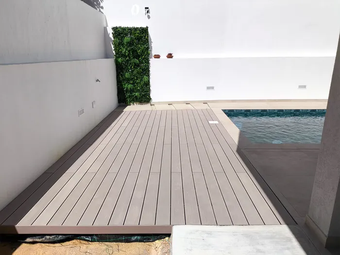 Terrasse composite CDECK® Beige Rose vue de face, bordant la piscine, mur végétal vertical et éclairages encastrés.