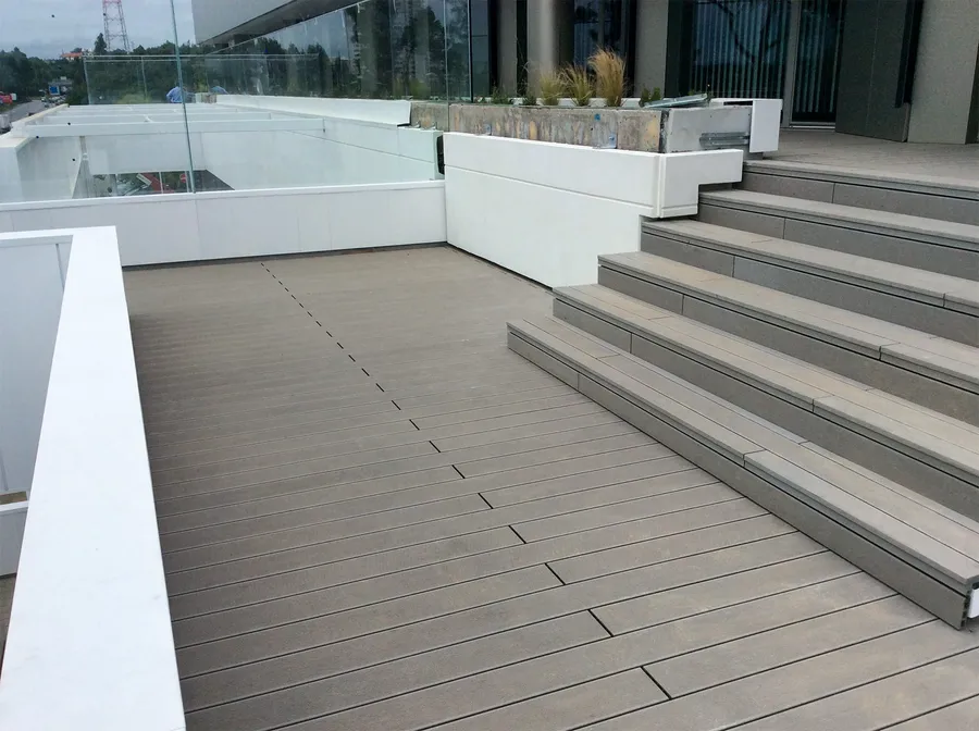 Balcony in CDECK® Original Grey composite decking with a staircase in the same material, glass balustrade and planters.