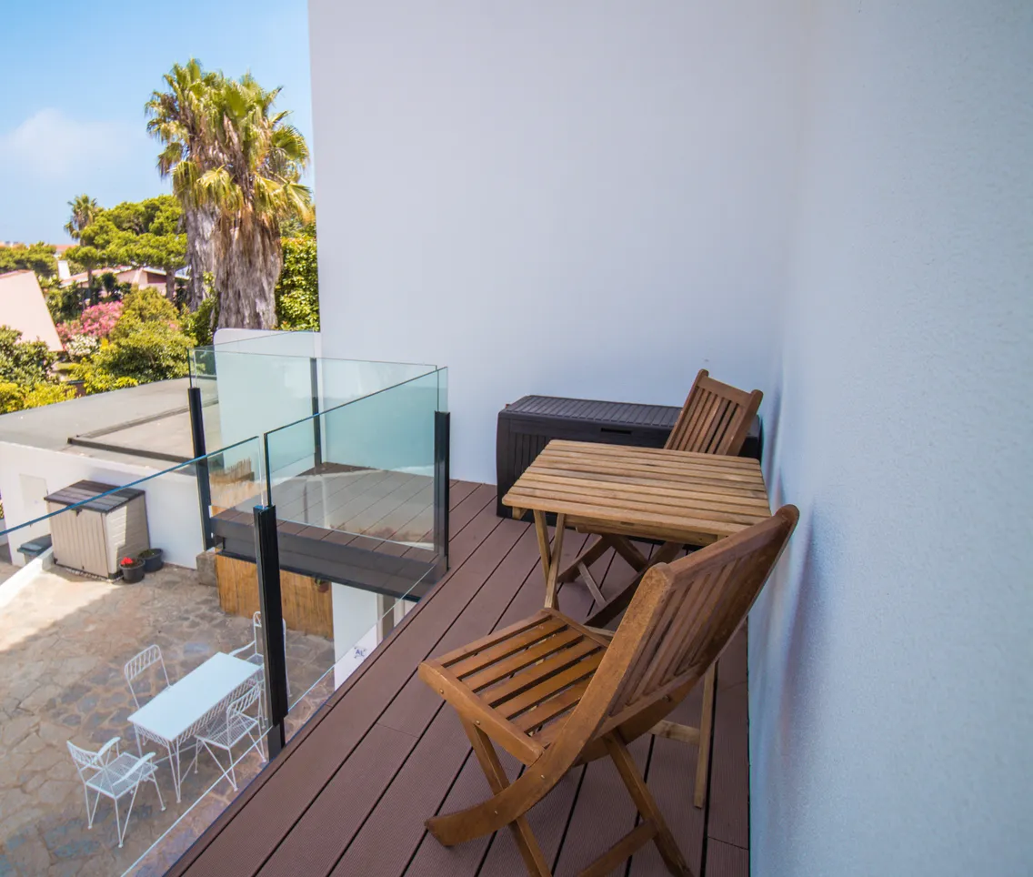Vue en hauteur du balcon en terrasse composite surplombant la cour et son mobilier extérieur.