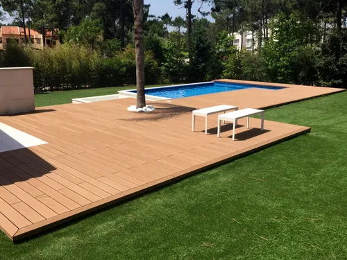CDECK Original® Redwood composite decking around the pool, with a palm tree in the centre, in Praia de Mira.
