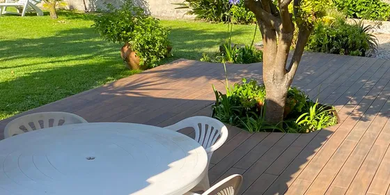CDECK WUUDE® composite decking in American Walnut in a garden, around a tree