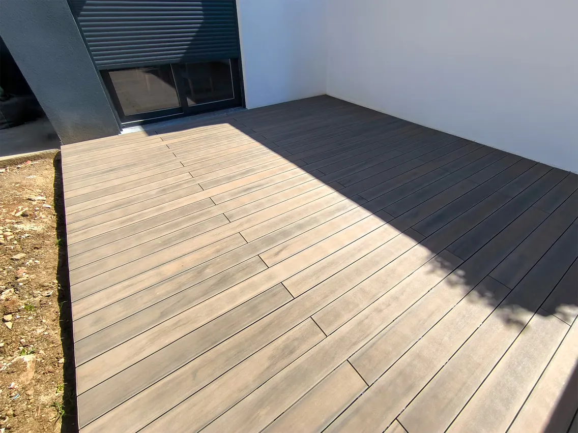 Diagonal view of the Natural Beech composite decking from the garden to the home's sliding window.