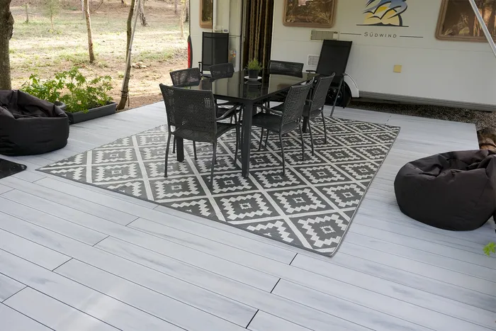 Vue d'ensemble de la caravane, son auvent et la terrasse composite Nordic Oak aménagée en salon.
