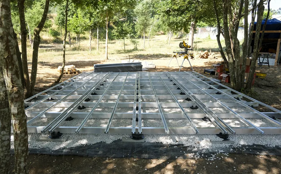 Ossature aluminium sur plots réglables et lit de gravier, avant la pose du platelage composite.