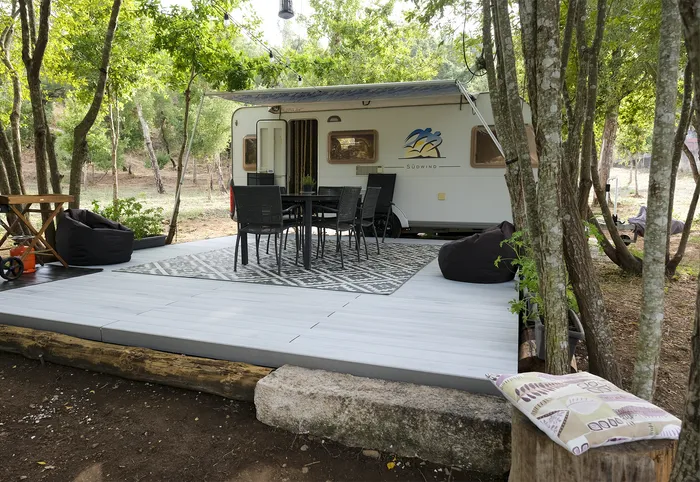 Terrasse CDECK WUUDE® Nordic Oak en sous-bois, entre caravane, salon repas et poufs, près de Coimbra.