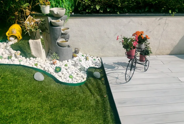 Rocaille décorative et fontaine miniature en bordure de la terrasse composite.