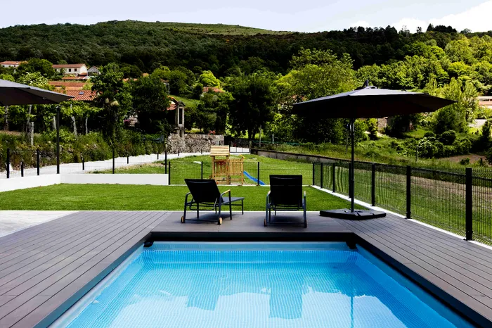 Terrasse CDECK Original® Chocolat en bord de piscine, transats et vue sur les collines de Montalegre.