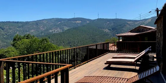 Varanda com deck compósito CDECK WUUDE® cor American Walnut e espreguiçadeiras, com vista para a serra