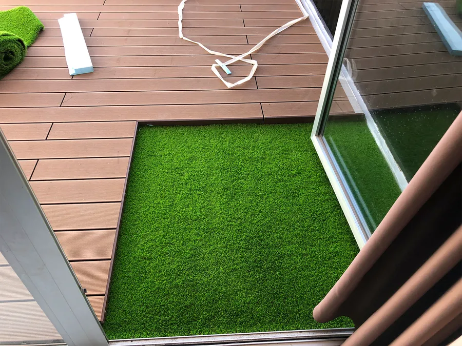 Insert de gazon synthétique posé au ras de la terrasse composite, finition en cours.