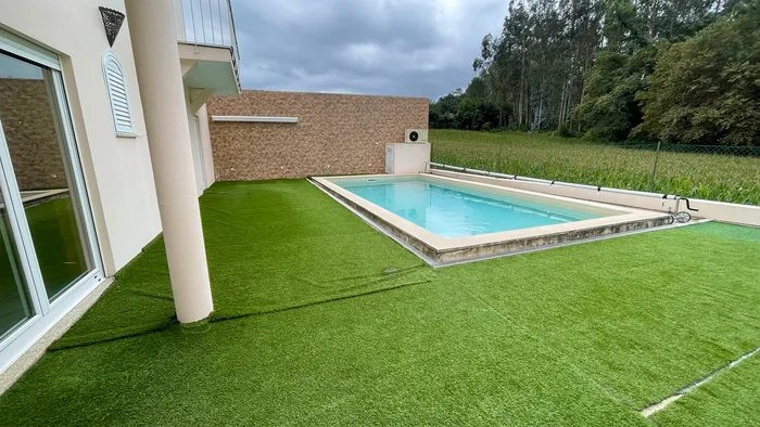 Gazon synthétique aux raccords visibles entre la façade de la maison et la piscine, avant la pose de la terrasse.