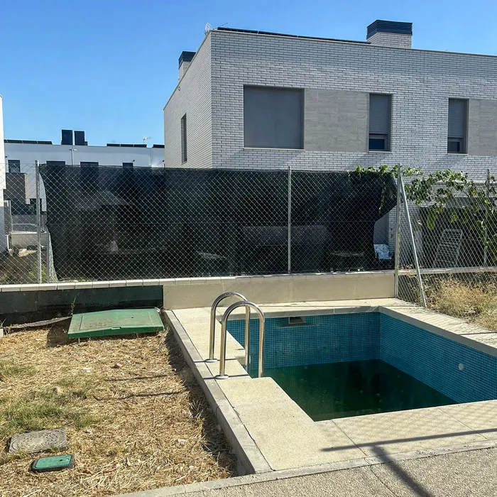 Pool and low wall with temporary wire fencing, offering no privacy from the neighbouring houses.