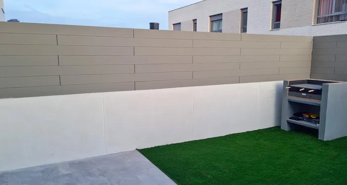 Raised garden wall with horizontal CWALL® Grey boards above the white base, barbecue in the corner.