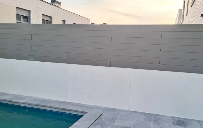Close-up of CWALL® Grey cladding in staggered boards on the wall beside the pool, in the late afternoon.