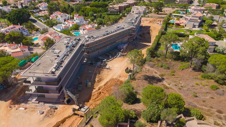 Vue aérienne du chantier en cours, bâtiments résidentiels entourés de villas et piscines privées.
