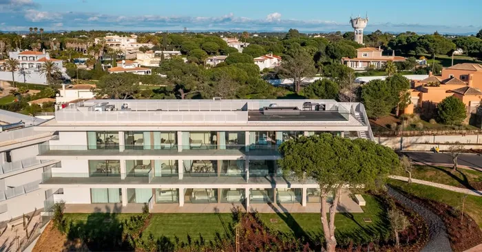 Vue aérienne de jour de l'immeuble Nomad Bay achevé, jardin paysager et château d'eau en fond.