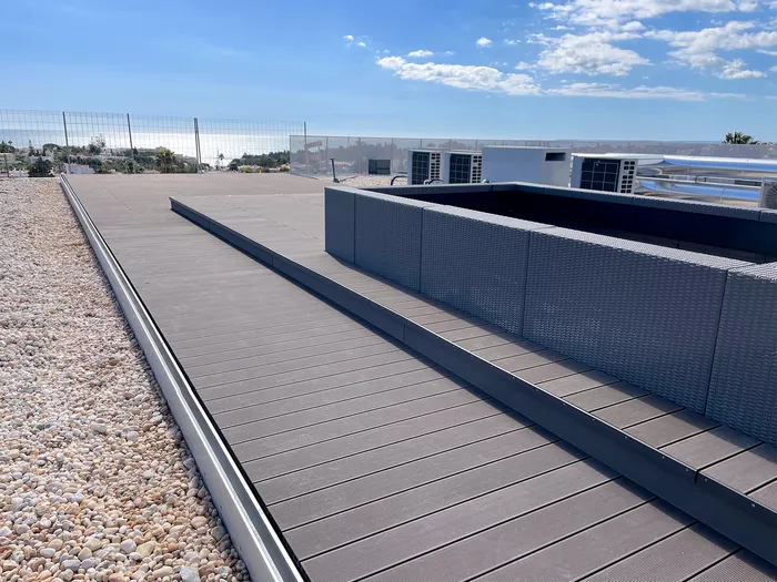 Allée en terrasse composite le long des unités techniques de climatisation, vue dégagée sur la mer.