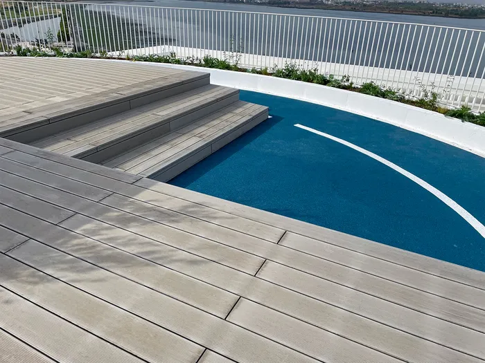 Vue aérienne des toits-terrasses avec piscines et lames composites grises, entre les deux ailes du bâtiment.