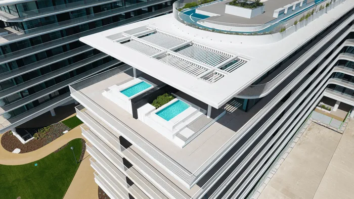 Vue aérienne du complexe avec toits-terrasses aménagés et zone encore en chantier au premier plan.