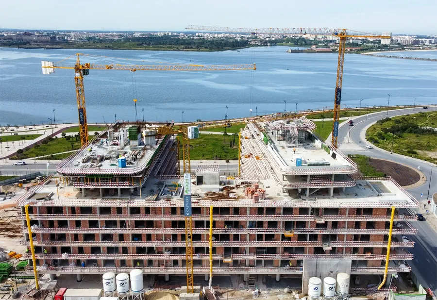 Vue aérienne du chantier en cours, grues de construction dominant le paysage urbain et l'estuaire.