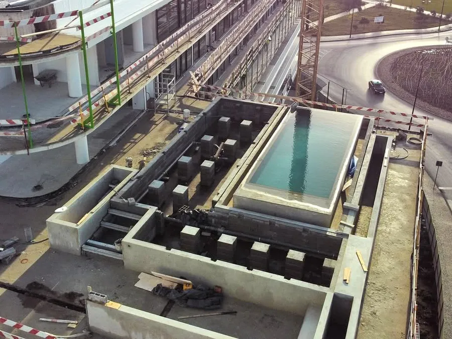 Bassin de piscine en cours de construction sur le toit, structure brute et étanchéité apparentes.