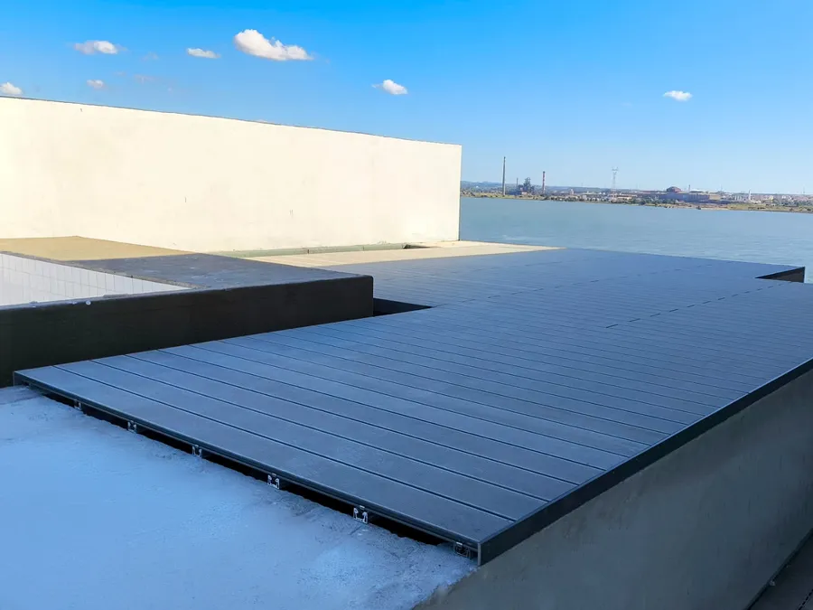 Lames composites CDECK Original® grises posées sur plots, prêtes à border la piscine du toit.