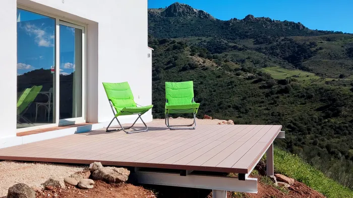 Terrasse composite en porte-à-faux vue depuis l'angle de la maison, structure métallique visible dessous.