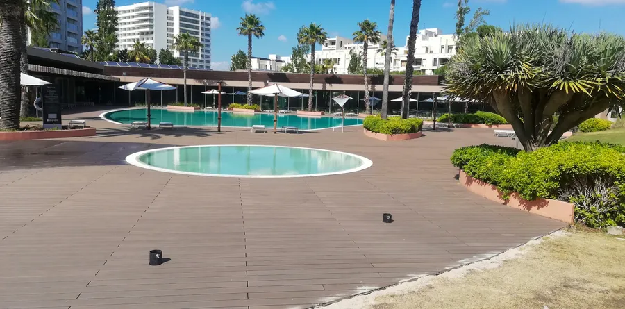 Nouvelle terrasse composite chocolat autour du bassin circulaire et de la piscine principale.