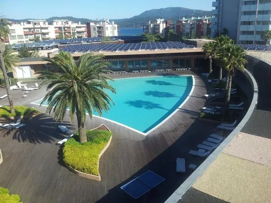 Terrasse et bar de piscine vus depuis les étages, collines de Tróia en toile de fond.